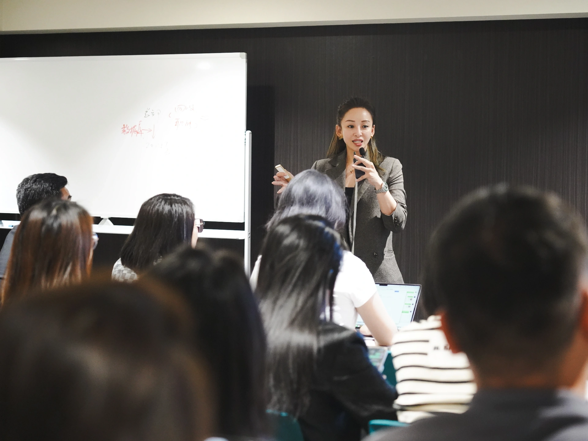 Samantha leading a sharing session in front of a whiteboard with professionals taking notes